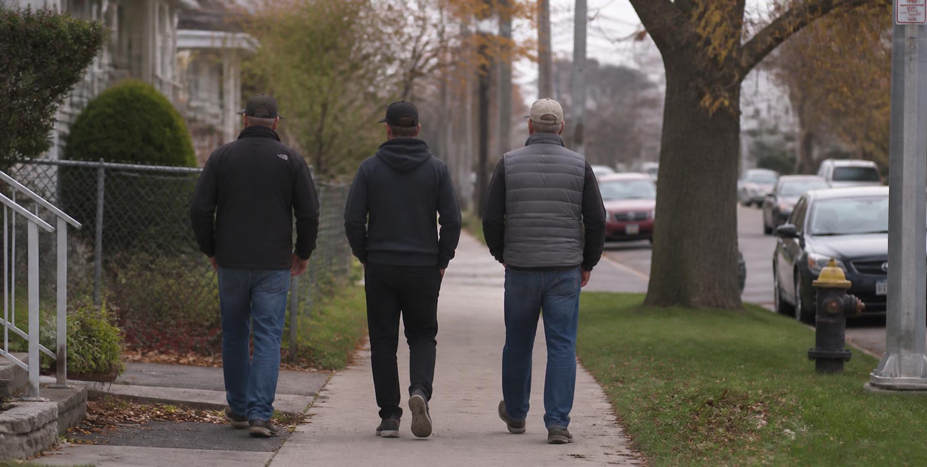 Men walking along a neighborhood sidewalk in a Baltimore-area residential street
